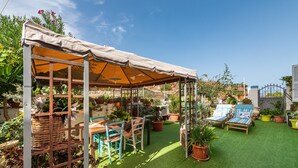 Une terrasse avec un revêtement de gazon synthétique, une pergola dotée d’un auvent, du mobilier d’extérieur et des plantes en pot.