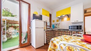 Une cuisine équipée d’un réfrigérateur, d’un four à micro-ondes et d’une table à manger recouverte d’une nappe à motifs de tournesols.
