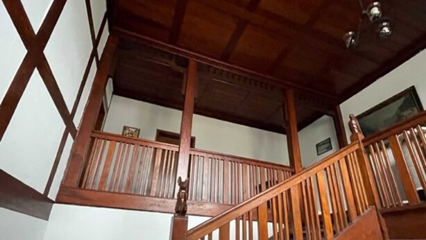 Una escalera de madera con barandilla que sube a un piso superior.