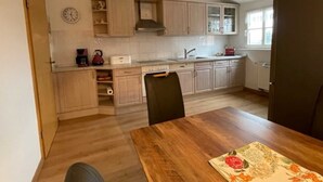 Una cocina compacta con armarios de madera clara, horno integrado y ventana que proporciona luz natural.