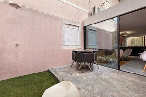 A modern patio with a glass door, a small grassy area, and a table with chairs. - Apartment 'LxFactory Terrace Lisbon Loft' with Terrace & Wi-Fi (Lisboa)