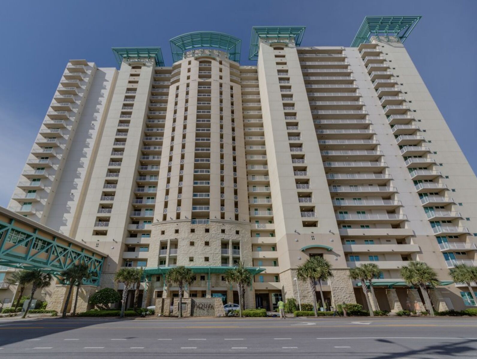 A high-rise hotel with multiple balconies, a central courtyard, and a prominent entrance with palm trees.