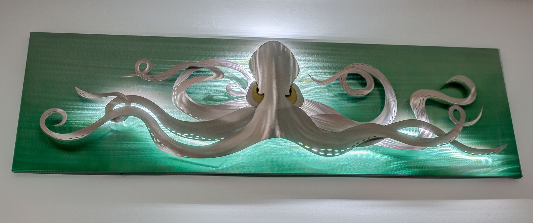 A metallic sculpture of an octopus on a green background.