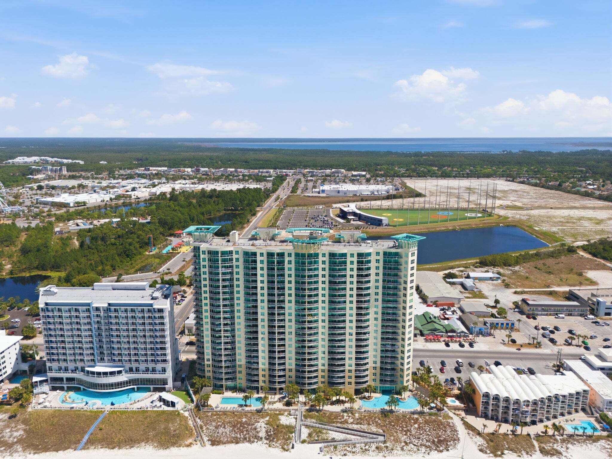 A high-rise hotel with multiple floors, a pool area, and a view of the surrounding landscape.