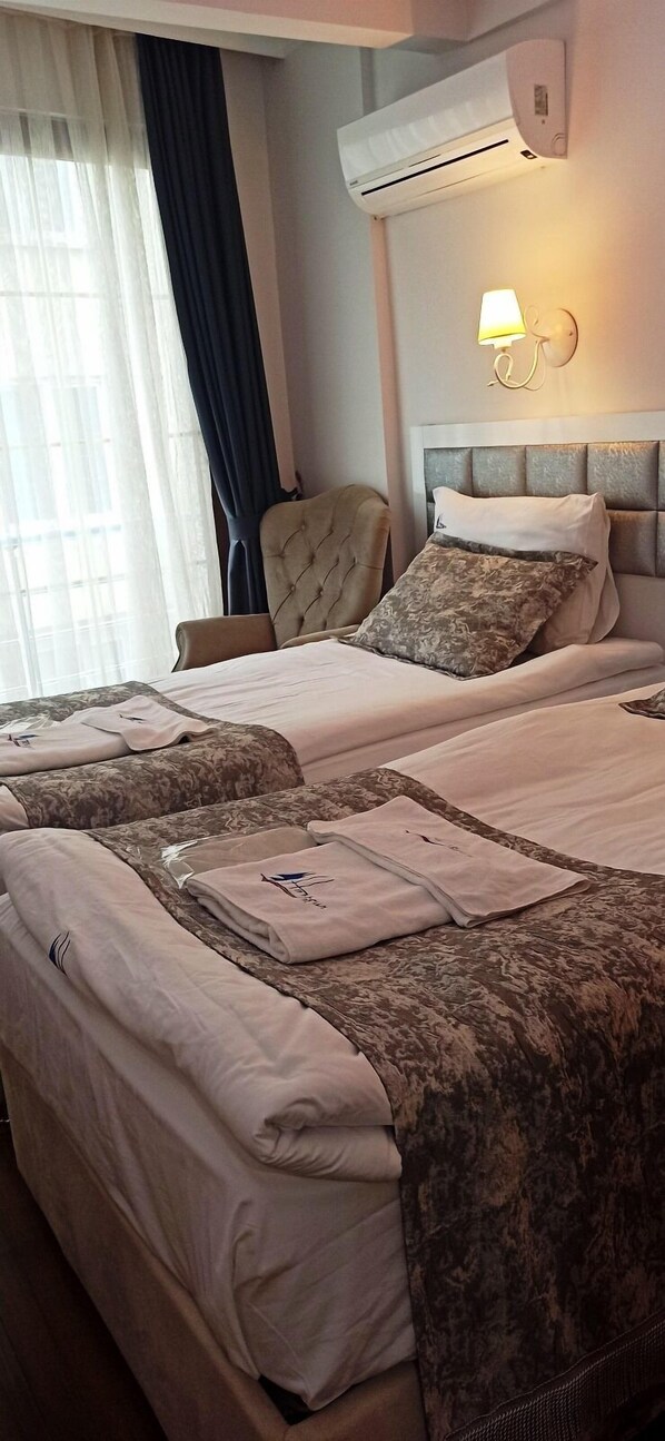A hotel room with a bed, a chair, an air conditioning unit, and a wall-mounted lamp. - Harbour Otel (Sinop)