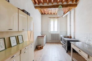 Une cuisine avec des meubles de rangement en bois, un radiateur, une fenêtre et un plan de travail.