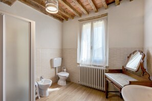 A bathroom with a toilet, bidet, sink, and a mirror.
