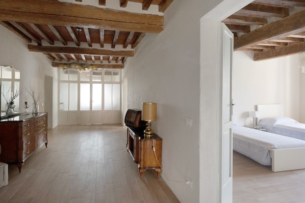 A room with a wooden ceiling, a bed, a dresser, and a lamp.