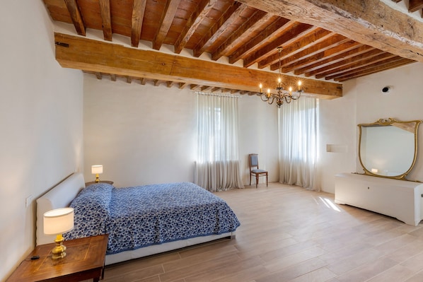 A bedroom with a bed, nightstands, a dresser, a chair, and a large mirror.