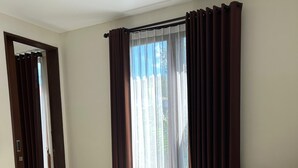 A hotel room with two beds, a large window with curtains, a door leading to another room, and a mirror on the wall. - The Calna Villa (Kuta)
