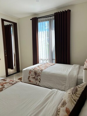 A hotel room with two beds, a large window with curtains, a door leading to another room, and a mirror on the wall. - The Calna Villa (Kuta)