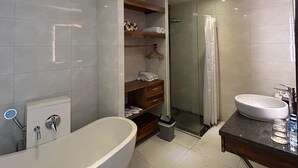 A modern bathroom with a large bathtub, a glass-enclosed shower, and a vanity with a sink. - The Calna Villa (Kuta)