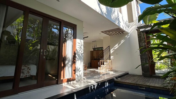 A modern house with a swimming pool, large windows, and a staircase leading to an upper level. - The Calna Villa (Kuta)