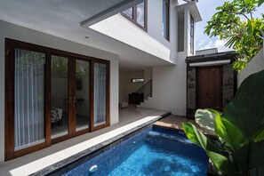 A modern house with a swimming pool, a staircase, and a large sliding glass door. - The Calna Villa (Kuta)