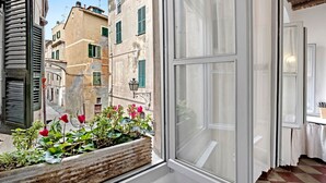 A window with a view of a narrow street, a wooden planter with flowers, and a white door. - Pet-Friendly Apartment Bilocale Merlino with Mountain View & Wi-Fi (Finale Ligure)