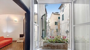 A narrow balcony with a flower planter, a red sofa, and a patterned floor. - Pet-Friendly Apartment Bilocale Merlino with Mountain View & Wi-Fi (Finale Ligure)