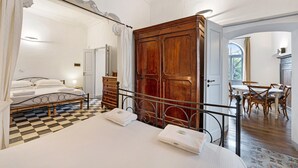 A bedroom with a bed, a wooden wardrobe, a dining area with chairs, and a checkered floor. - Pet-Friendly Apartment Quadrilocale Camelot with Mountain View, Balcony & Wi-Fi (Finale Ligure)
