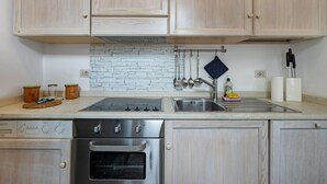 A kitchen with wooden cabinets, a stainless steel oven, a sink, and a white brick backsplash. - Pet-Friendly Apartment Quadrilocale Camelot with Mountain View, Balcony & Wi-Fi (Finale Ligure)