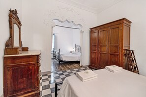 Une chambre avec un sol à carreaux, un lit, une armoire en bois et un miroir.