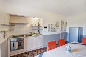 Une cuisine équipée d’une cuisinière, d’un four, d’un évier et d’un réfrigérateur. On y trouve une table à manger avec des chaises, ainsi qu’un objet décoratif.