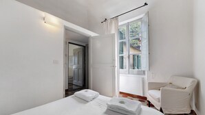 Quarto com cama, cadeira, janela e porta.