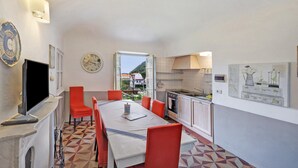 Uma cozinha compacta com área de refeições, televisão e um relógio na parede.