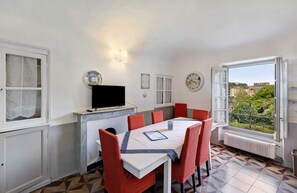 A dining area with a table, chairs, a television, and a window with a view.