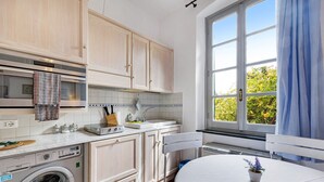 A compact kitchen with a washing machine, a sink, and a window with curtains.