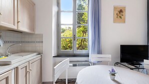 A room with a window, a bed, a TV, and a small table.