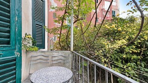 A balcony with a metal railing, a small round table, and chairs.