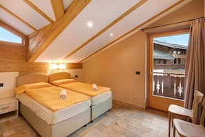 A bedroom with a bed, a nightstand, a chair, a balcony with a view, and a wooden ceiling.