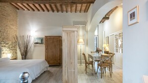 A bedroom with a bed, wooden wardrobe, and a dining area with a table and chairs. - Studio "Radicondoli" with Balcony & Wi-Fi (Radicondoli Siena)