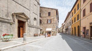 A street with stone buildings, a bench, and a cart with flowers. - Studio "Radicondoli" with Balcony & Wi-Fi (Radicondoli Siena)