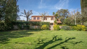 A two-story house with a stone facade, a tiled roof, and a well-maintained lawn.