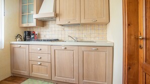 A kitchen with wooden cabinets, a tiled backsplash, a coffee maker, and a sink.