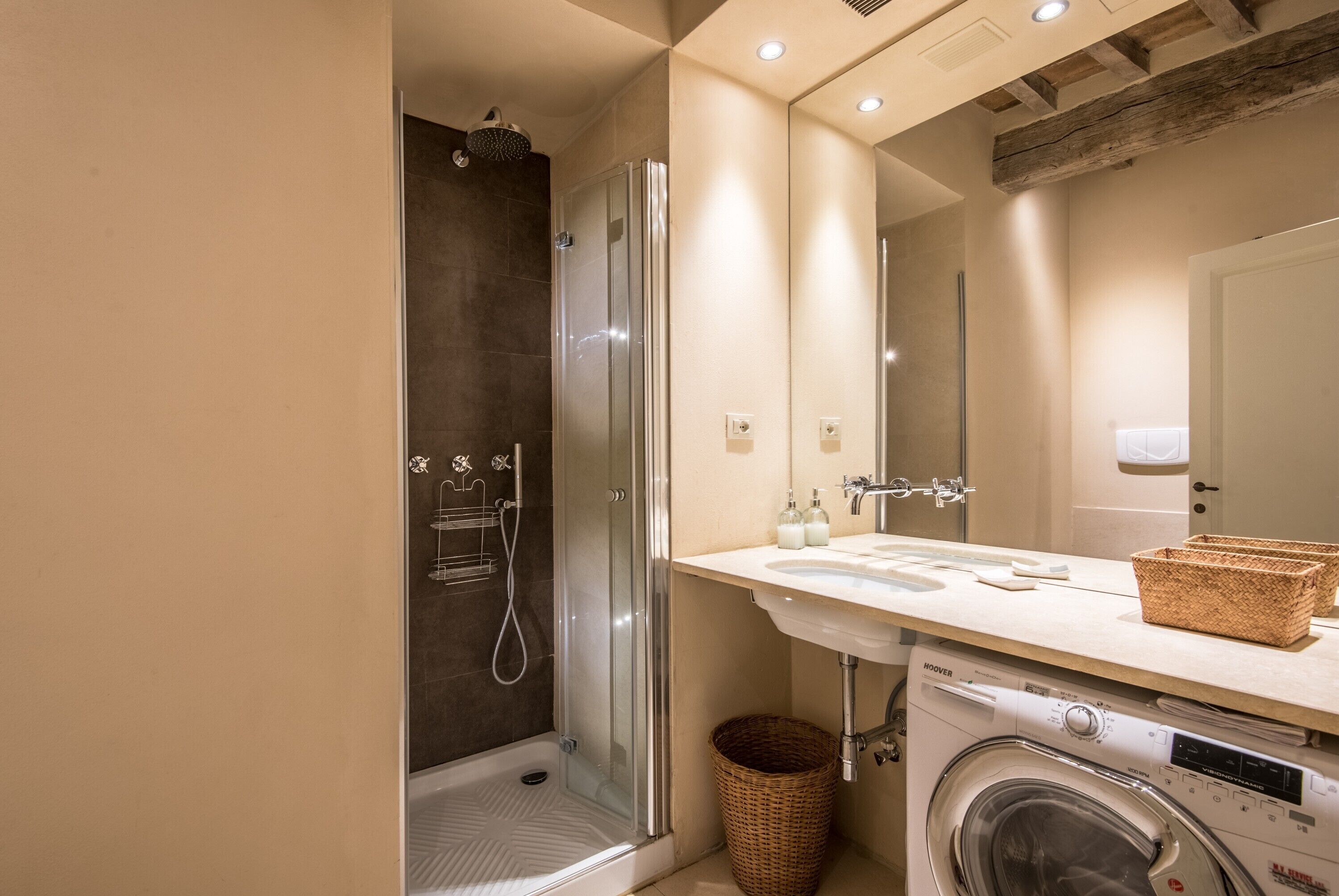Ein modernes Badezimmer mit einer Duschkabine, einem integrierten Waschbecken und einer Frontlader-Waschmaschine.