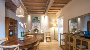 Un coin repas comprenant une table en bois, des chaises, un luminaire suspendu et un meuble avec des portes en verre.