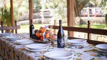 A table set outdoors with plates, a bottle of wine, and a fruit arrangement.