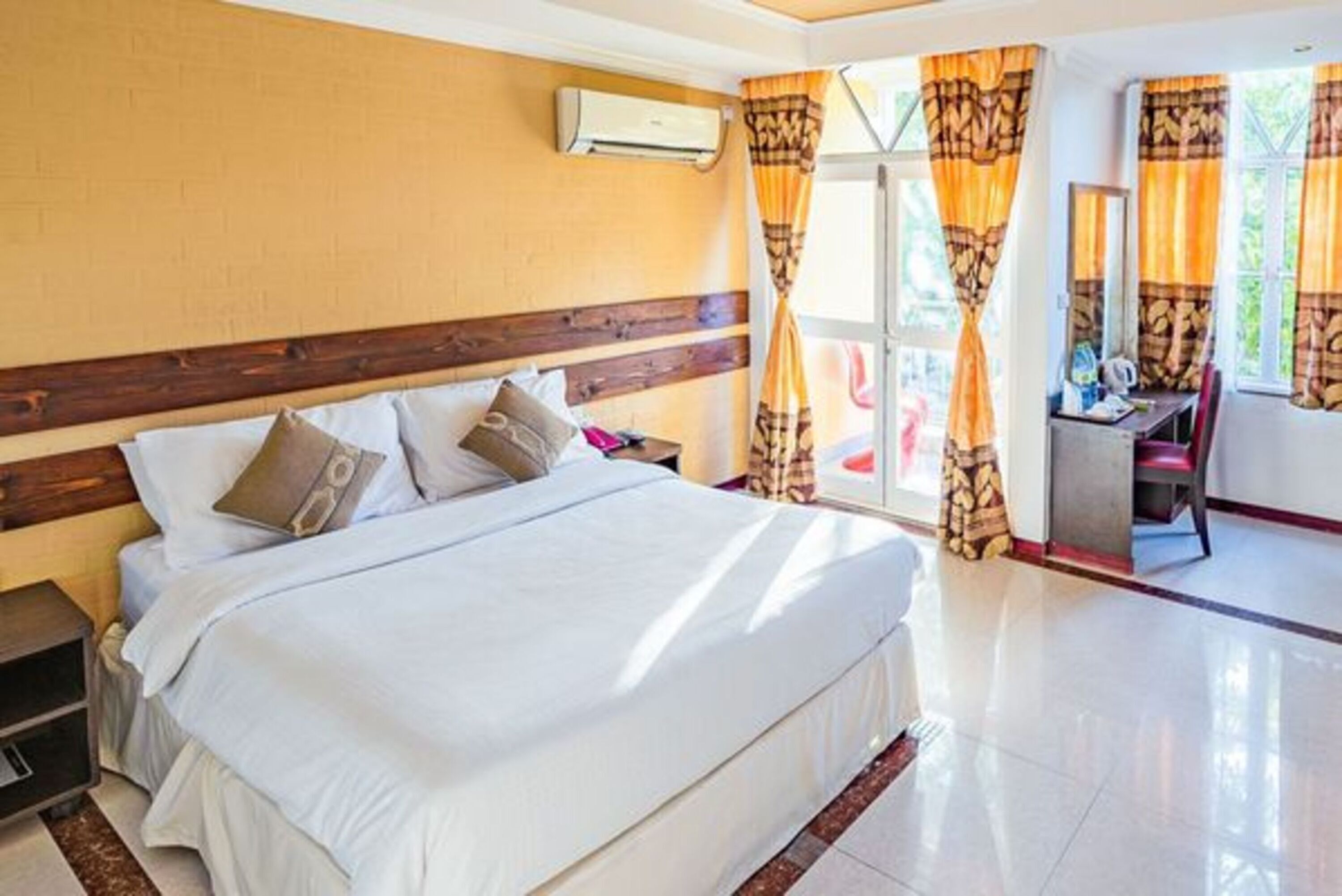 A hotel room with a large bed, a desk, and a chair.