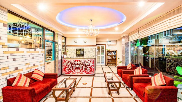 A hotel lobby with red sofas, a reception desk, and a chandelier. - RIJ HULHUMALE (Hulhumalé)