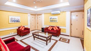 A hotel lobby with two red sofas, a glass coffee table, and two paintings on the walls. - RIJ HULHUMALE (Hulhumalé)