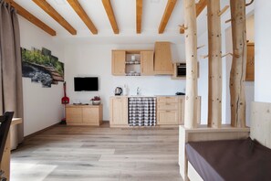 A modern kitchen with wooden cabinets, a flat-screen TV, and a dining area with a bench.
