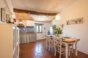 A kitchen with a wooden ceiling, tiled backsplash, and a dining area with a table set for two.