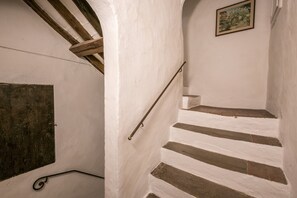 A staircase with white walls and wooden beams, a metal handrail, and a picture on the wall.