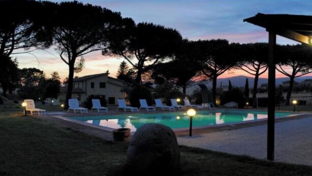 A pool area with lounge chairs and a covered seating area.