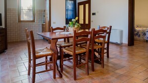 A dining area with a wooden table and chairs, a window, and a tiled floor. - Apartment "Alba" in Maremma with Terrace, Outdoor Pool, and Wi-Fi (Montemassi)