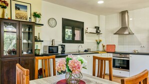 Una cocina con mesa, sillas, un reloj y un microondas.
