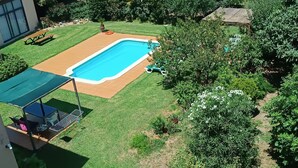 Un patio trasero con piscina, mesa de picnic y zona de estar cubierta.
