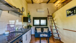 Cocina compacta con estufa, pileta y un pequeño comedor con sofá y mesa.