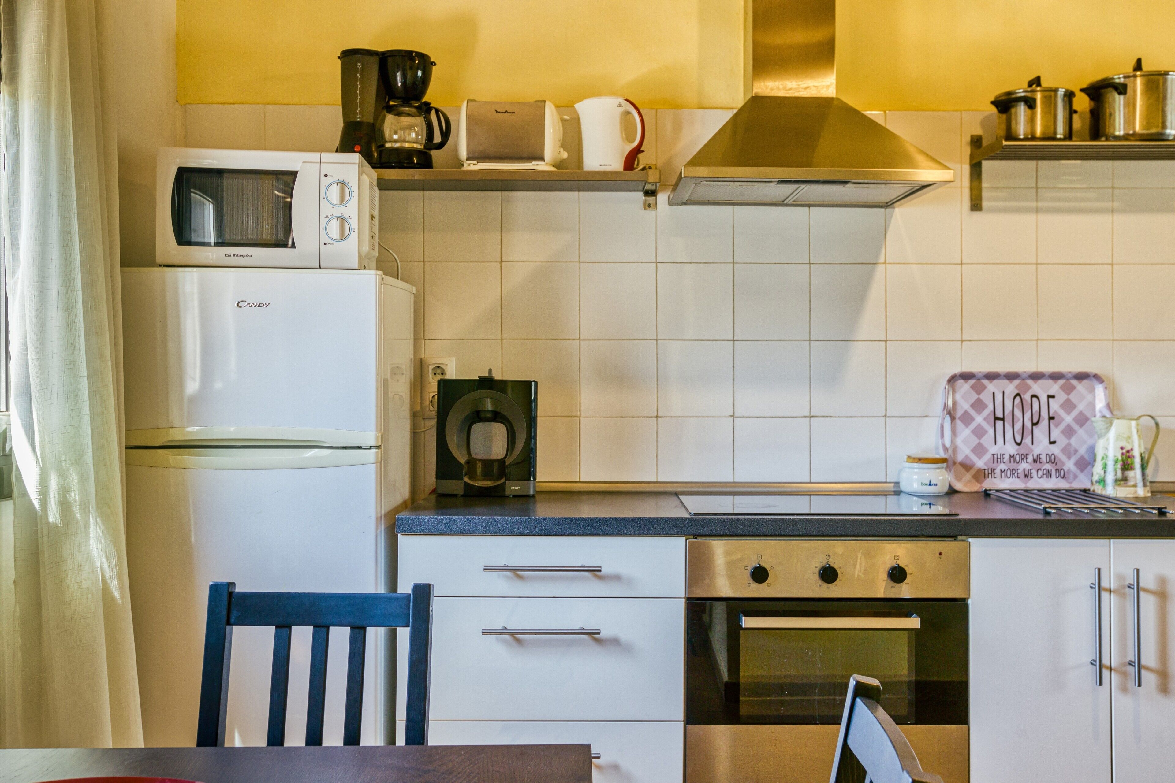 Een keuken met een magnetron, broodrooster, koffiezetapparaat en een bord waarop 'HOPE' staat.